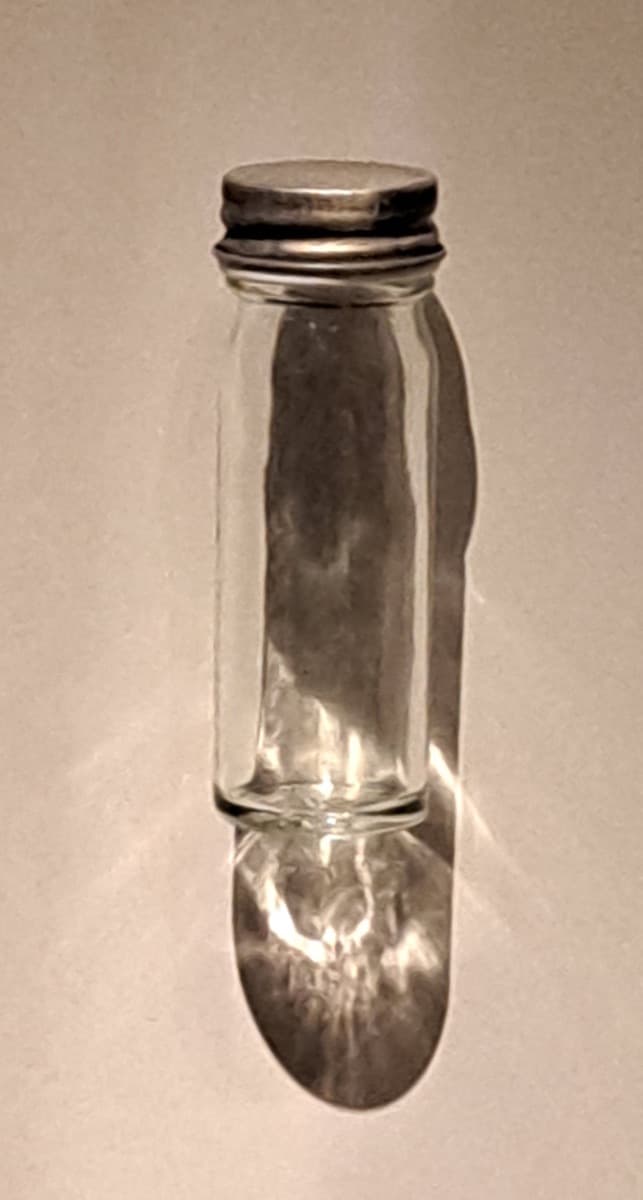 A small glass sample jar in a museum case.
